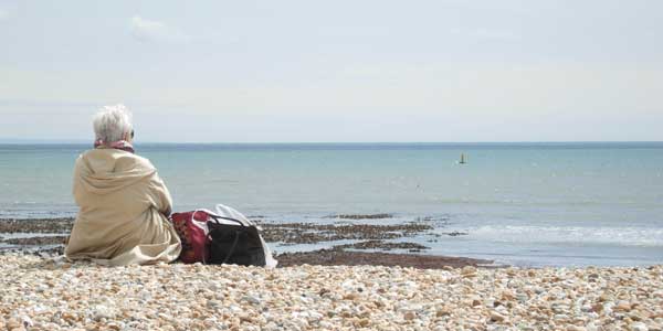 A lady sat on the beach looking out to sea